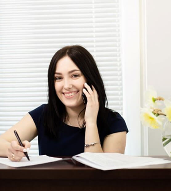 smiling dental team member taking noted behind front desk